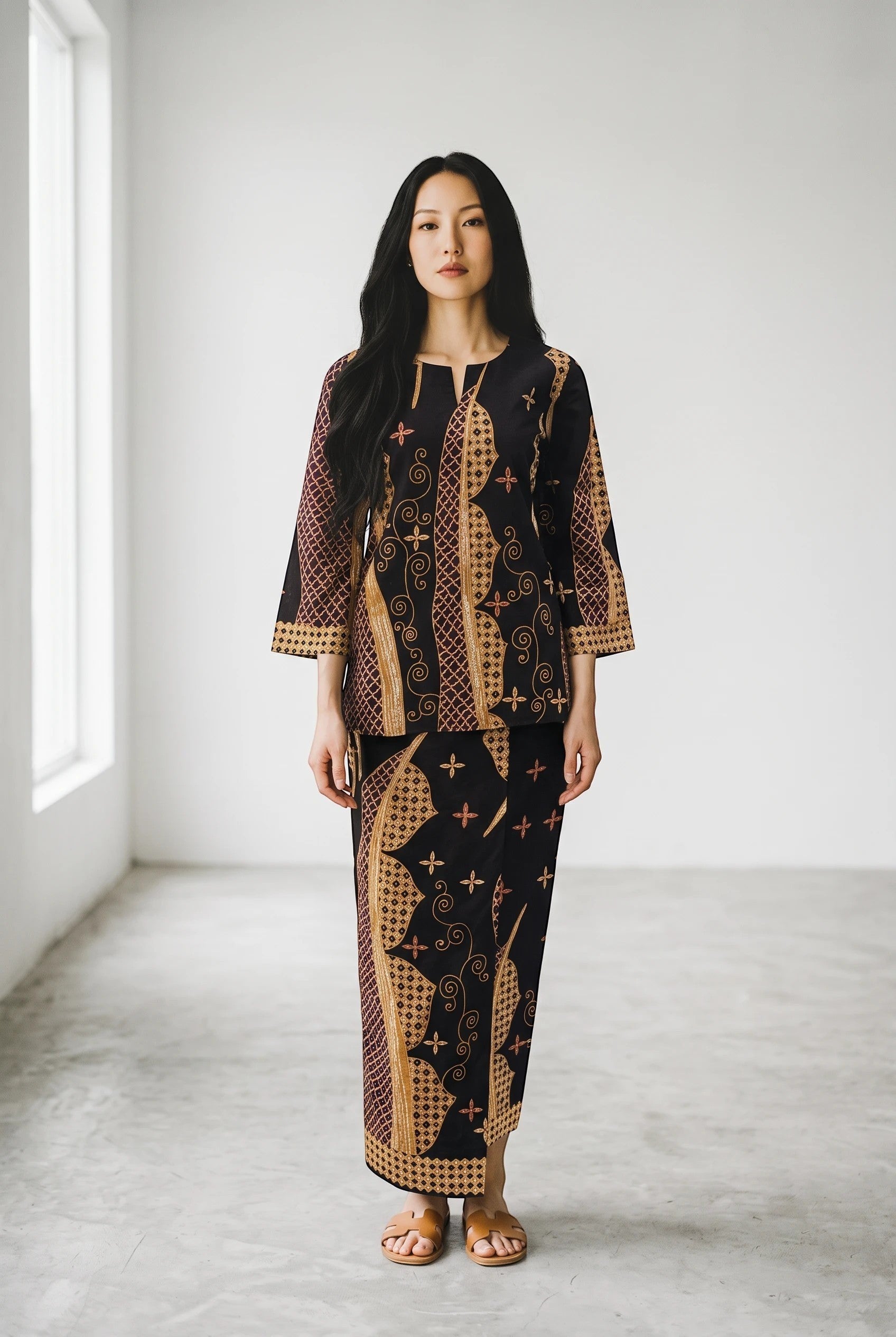 Model wearing a dark blue PARCA batik-print cotton top and matching maxi sarung with flared sleeves.