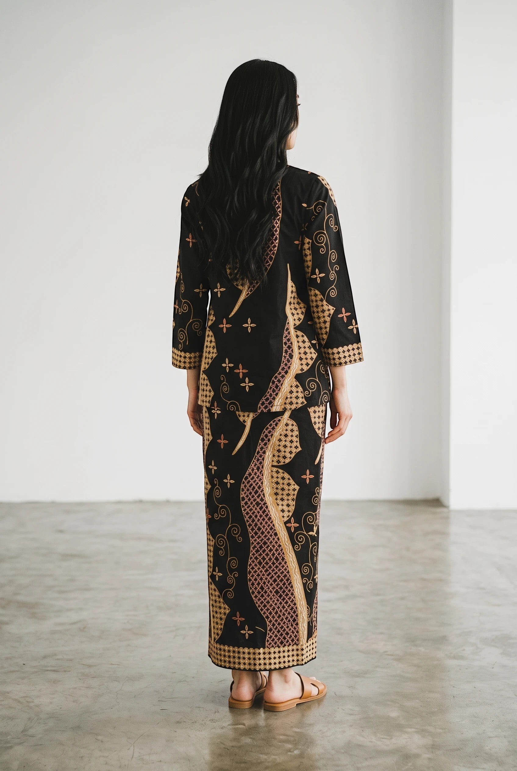 A model wearing a dark blue PARCA cotton top and matching maxi sarung with traditional batik-inspired patterns.
