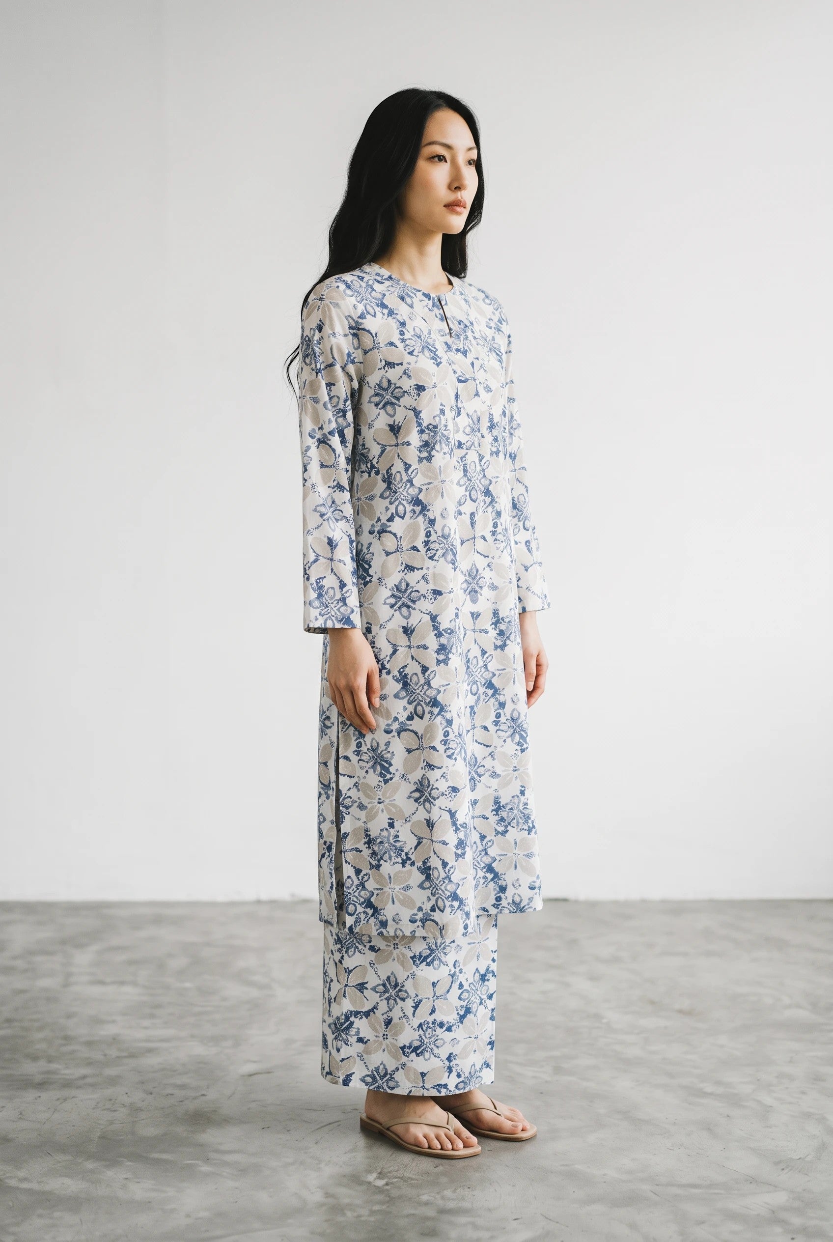 A model wearing a PARCA white and blue floral print cotton midi top and matching maxi sarung in a studio setting.