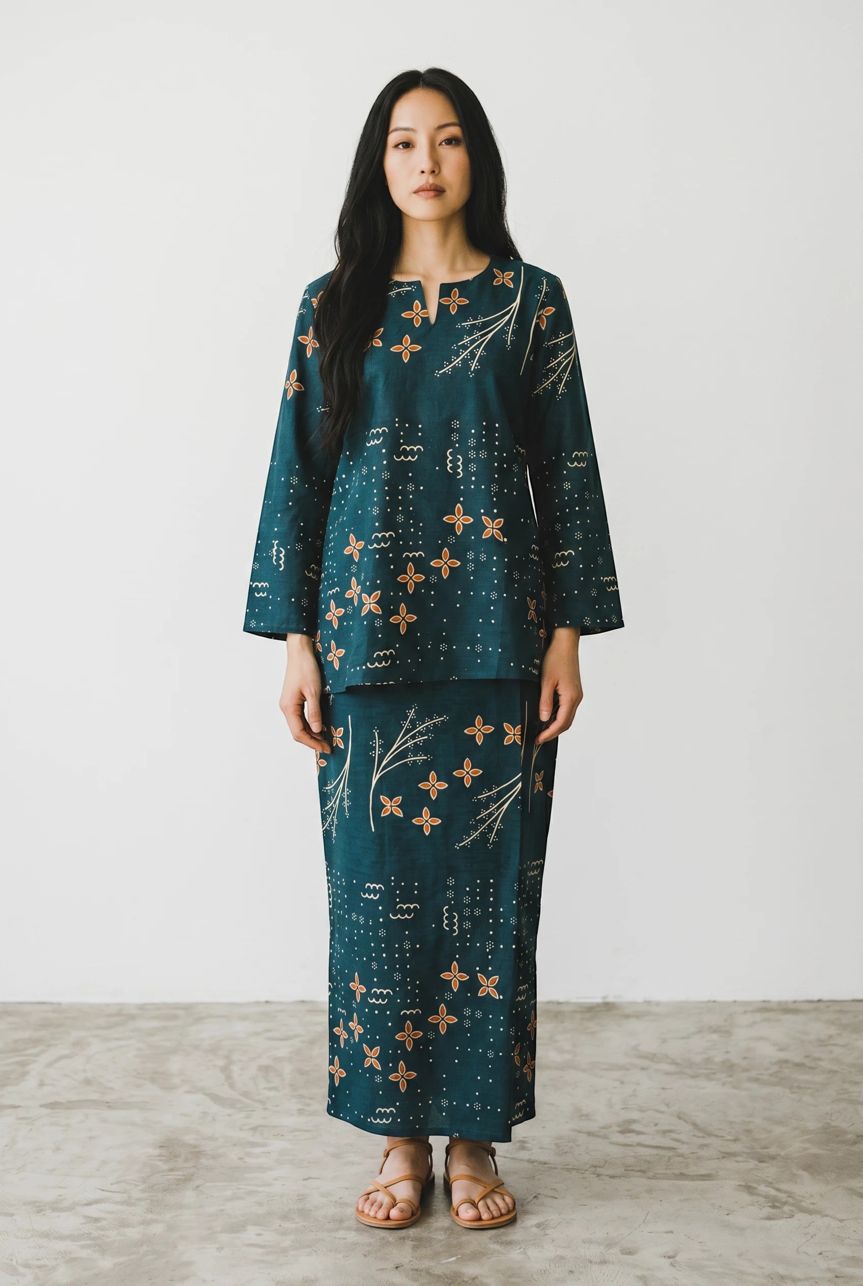 Model wearing a green PARCA loose-fit cotton top and matching maxi sarung with a floral and geometric print.
