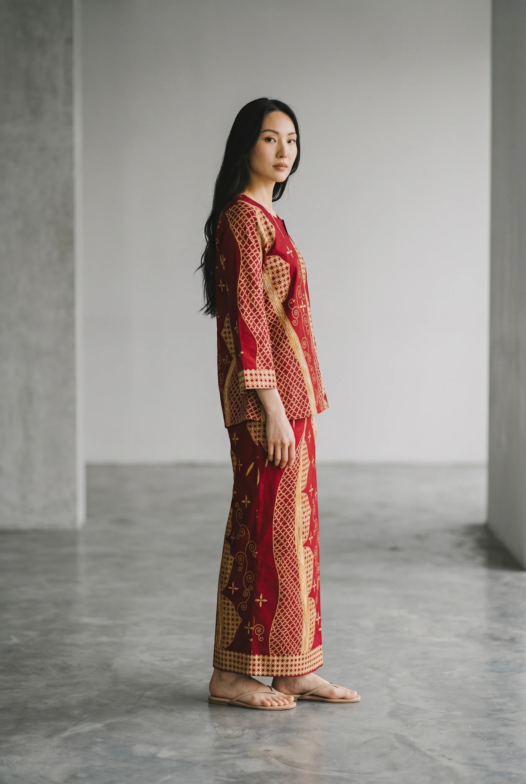 Model wearing a maroon cotton top and matching maxi sarung with traditional patterns by PARCA in a minimalist studio.