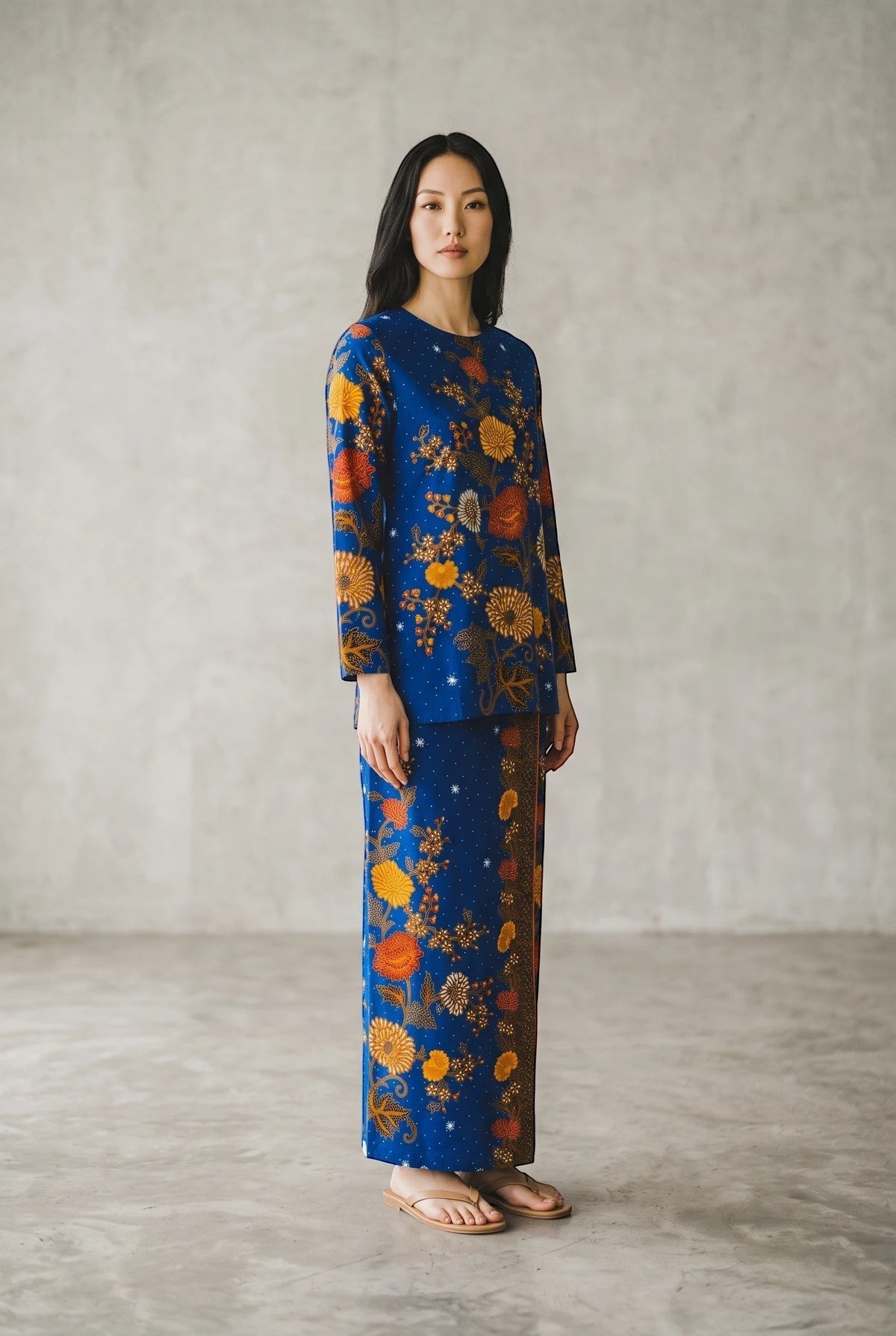 Model wearing a PARCA royal blue cotton top and matching maxi sarung with a vibrant floral batik print.