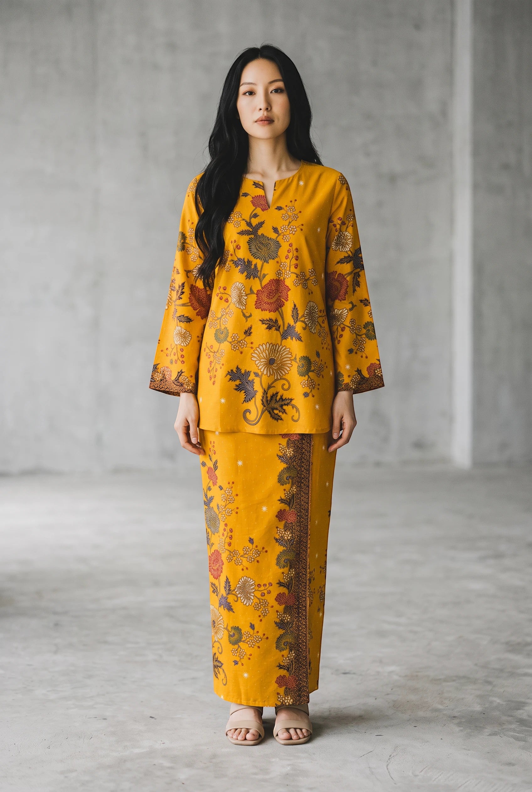 A model wearing a yellow PARCA cotton top and matching sarung with a floral batik-style pattern in a studio setting.