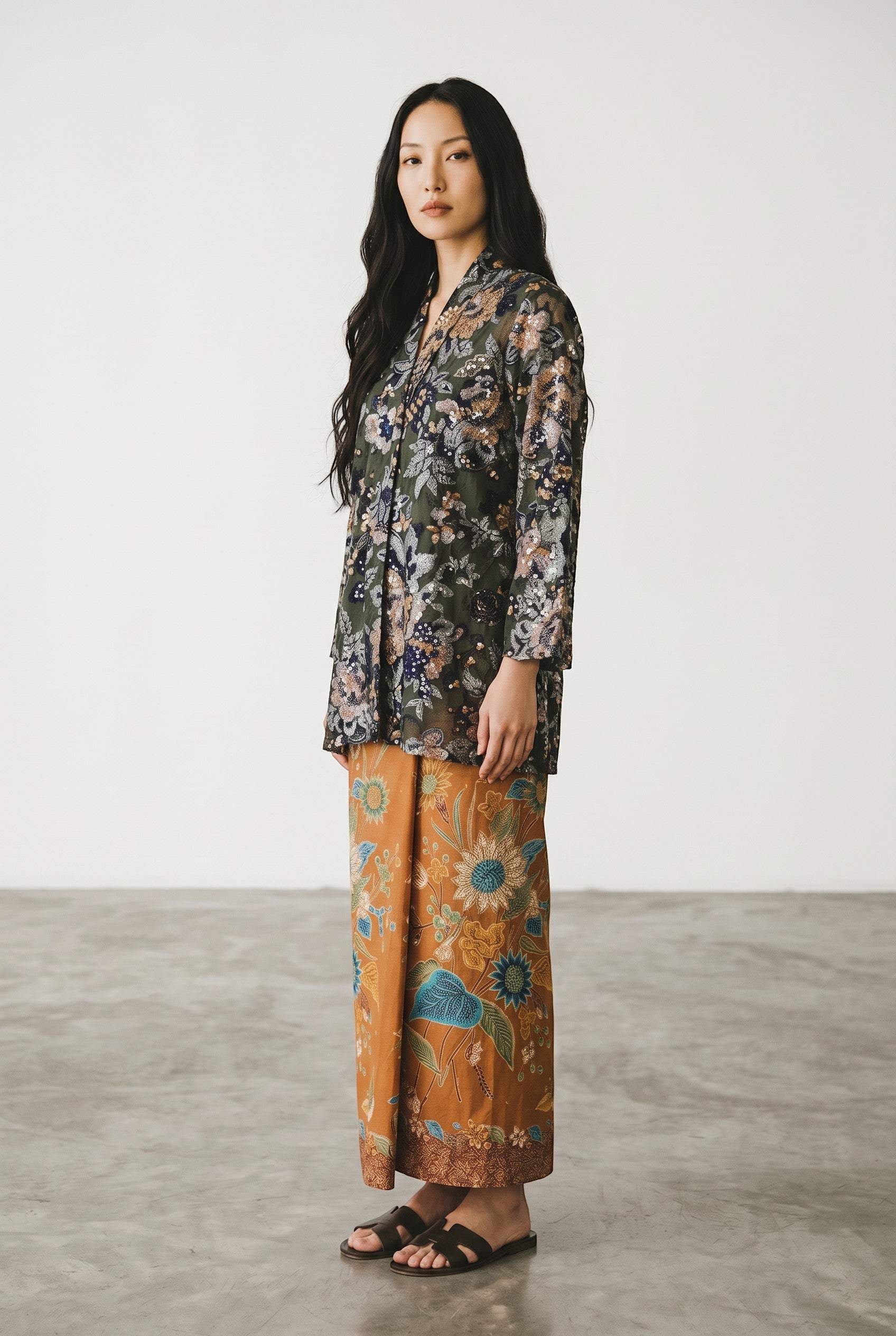 PARCA Naira Kimono Kebaya in black with intricate floral embroidery and V-neck. Paired with a brown batik sarong.