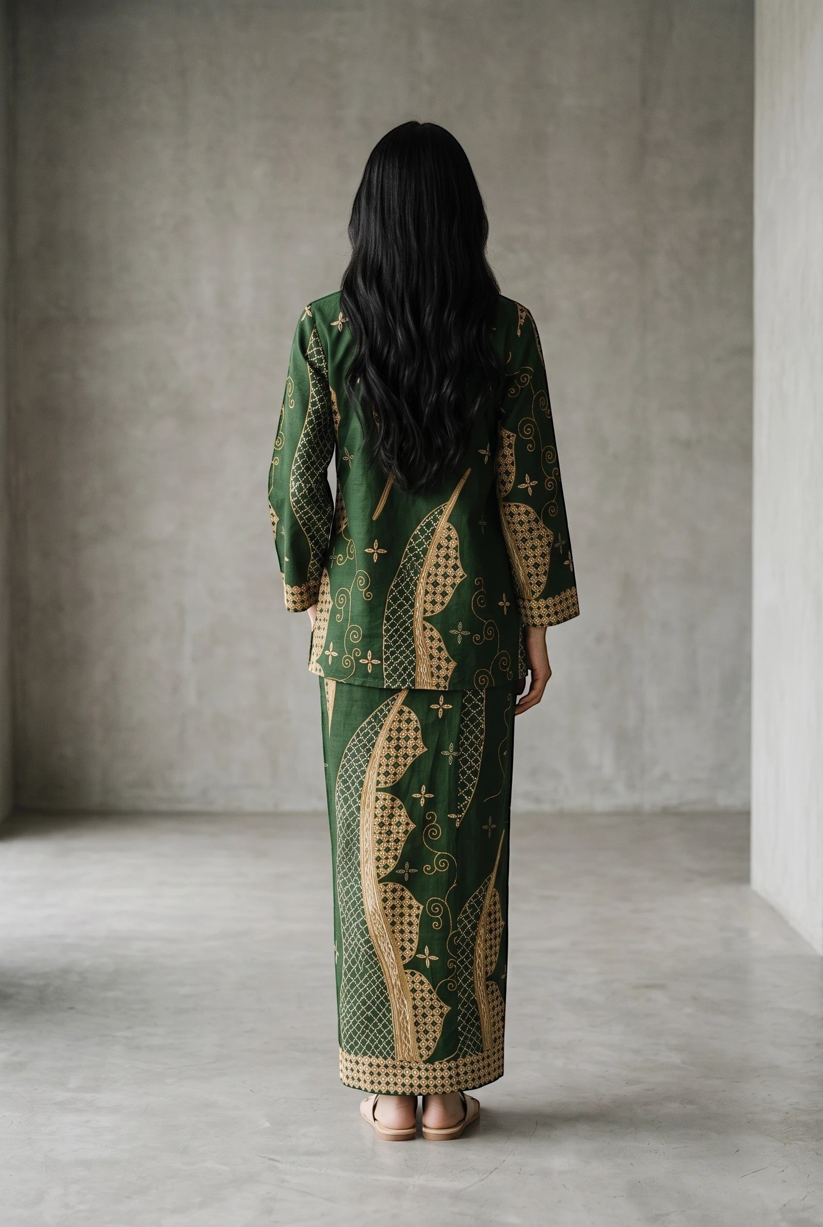 Back view of a woman wearing a green cotton top and matching maxi sarung with traditional batik patterns by PARCA