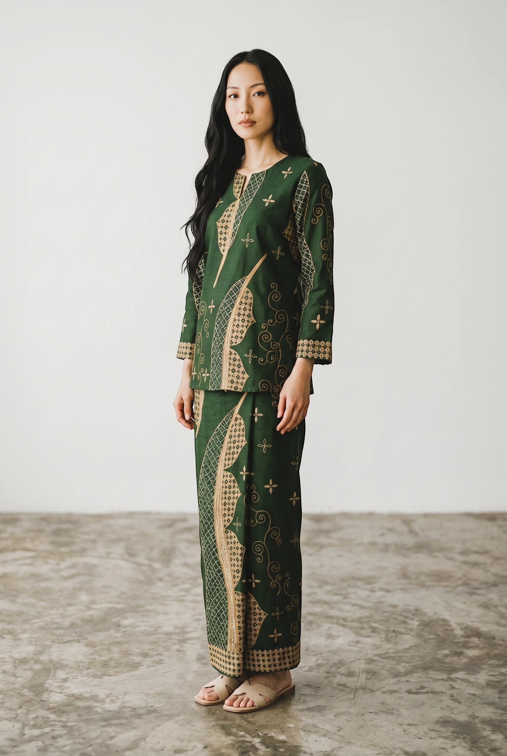 Model wearing a green PARCA cotton top and matching maxi sarung with traditional batik-inspired patterns.