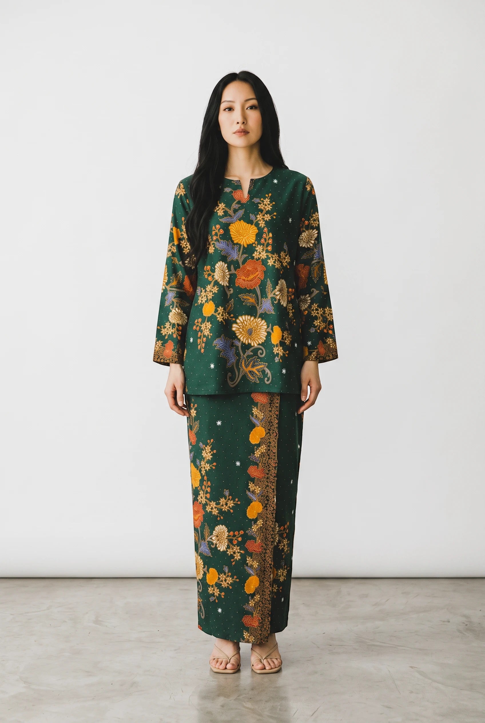 A model wearing a PARCA green cotton set featuring a long-sleeved top and matching maxi sarung with floral batik print