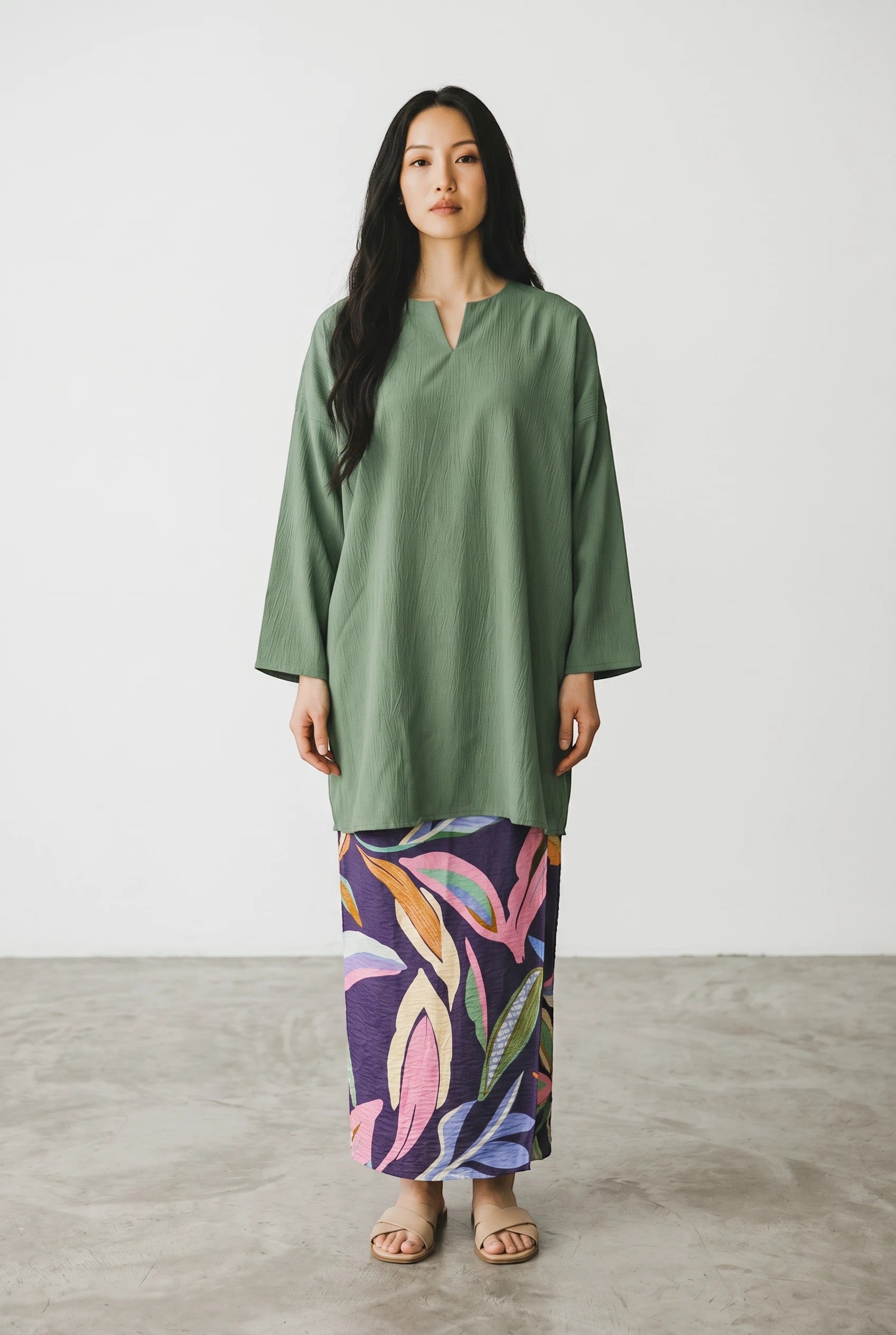 A model wearing a PARCA green oversized midi top with a round neckline and V-slit, paired with a patterned skirt.