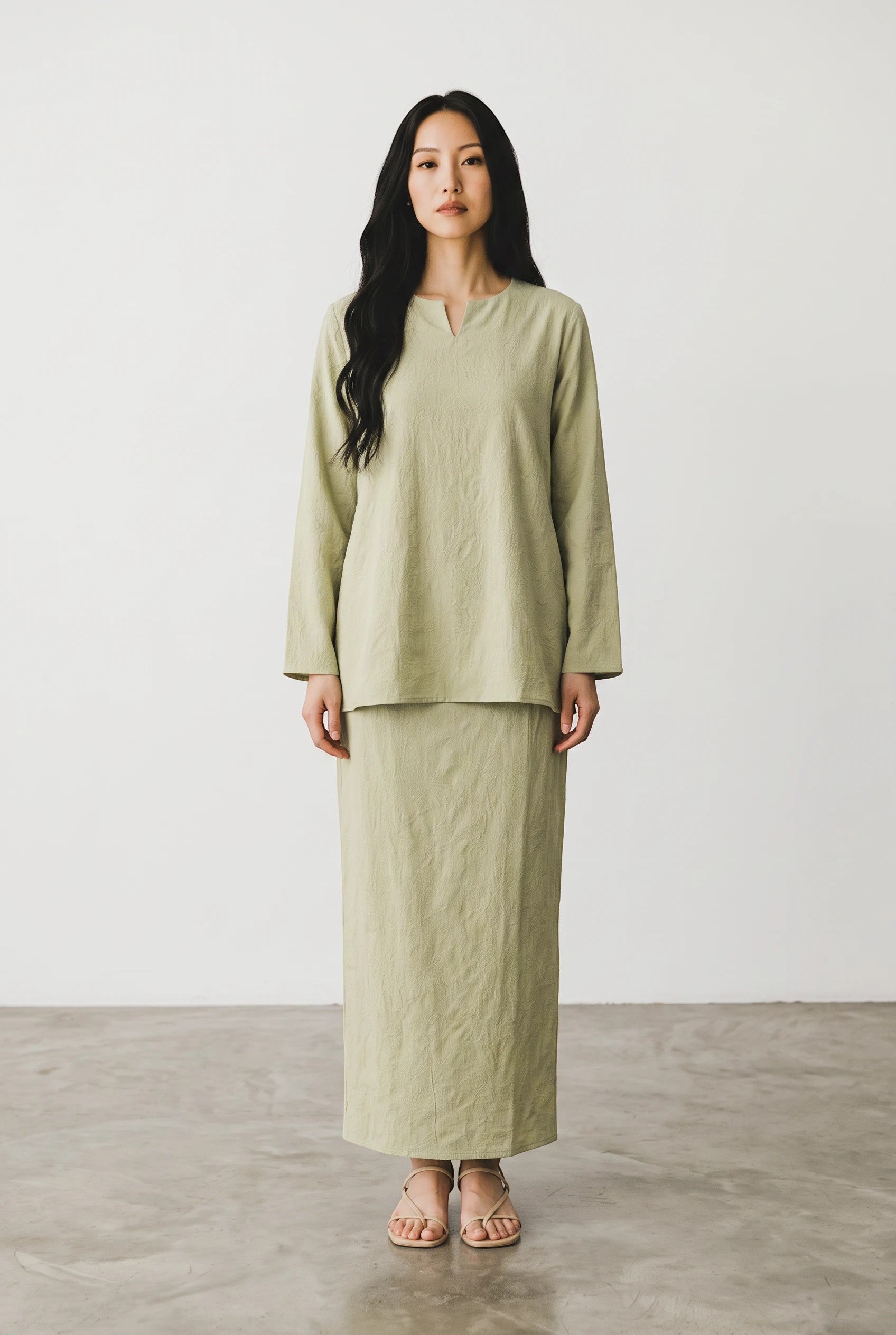 Model wearing a PARCA Laili pistachio green cotton top and matching maxi sarung skirt with a round neckline.