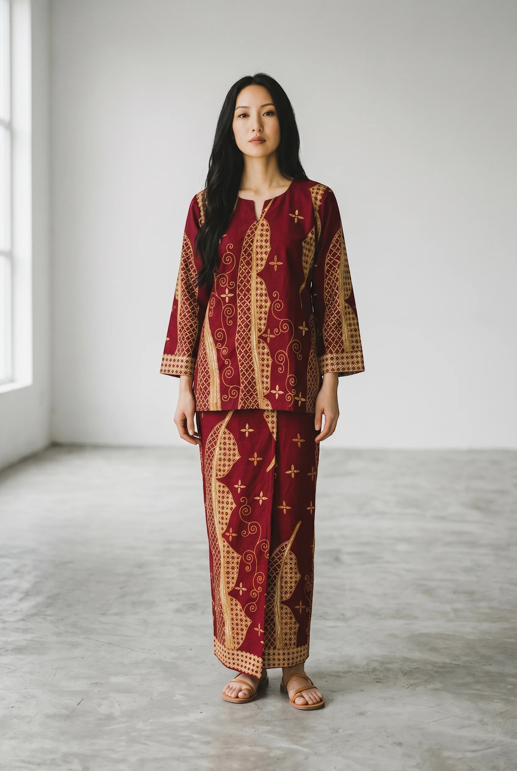 Model wearing a maroon cotton top and matching maxi sarung with traditional gold patterns by PARCA