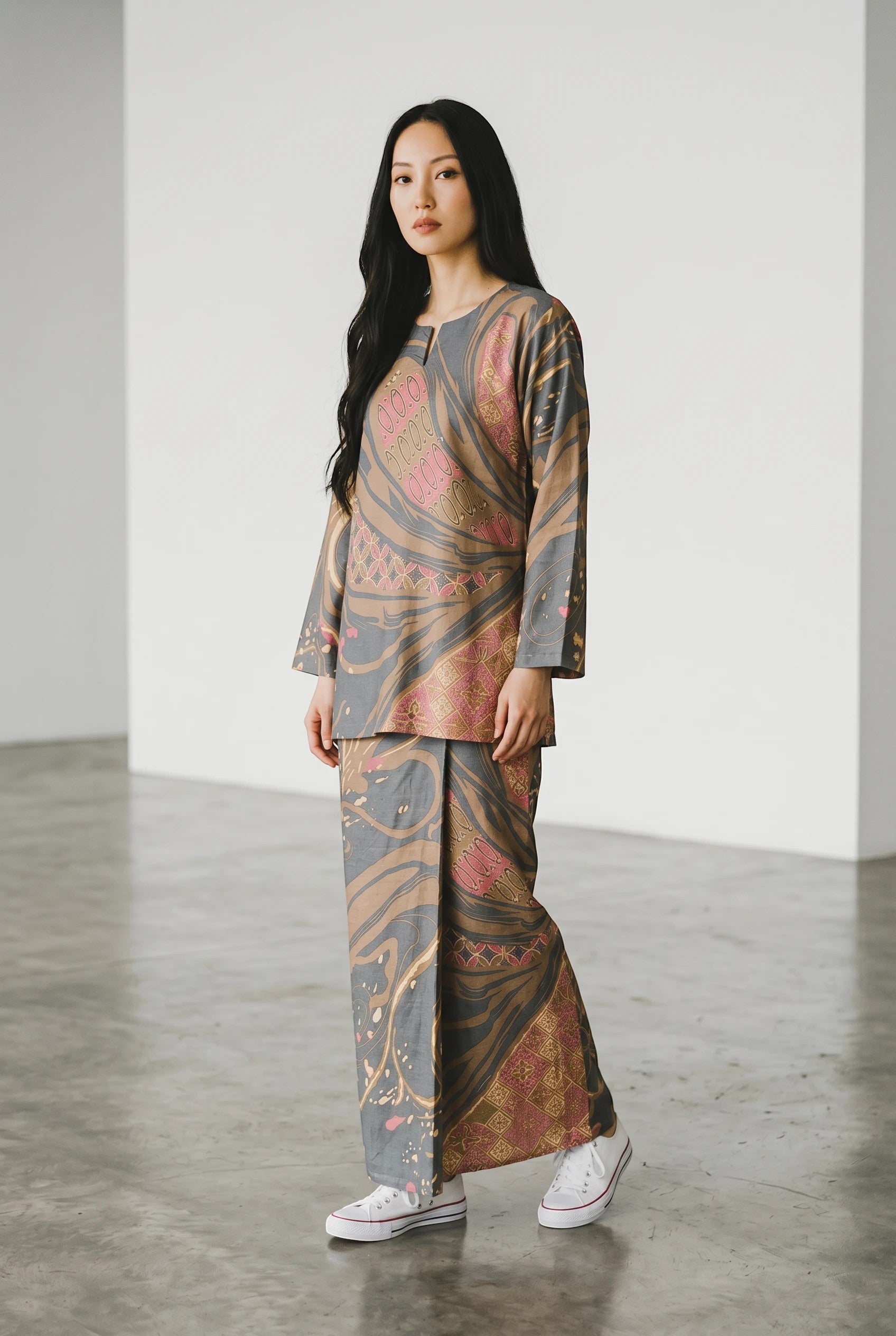 Model wearing PARCA Natalia in Pink batik set featuring grey and pink abstract patterns with a long skirt and top.