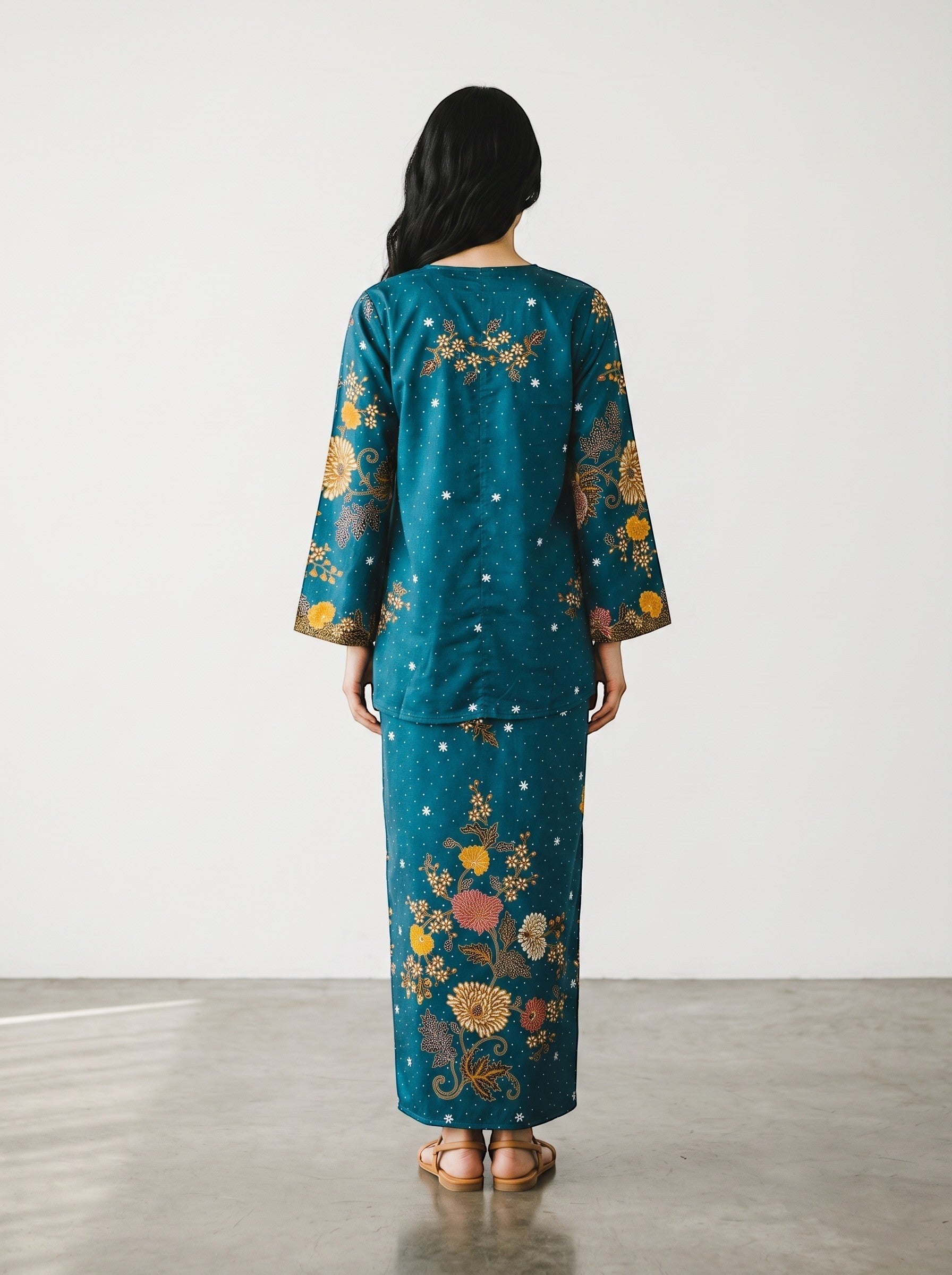 PARCA Nayra flared cotton top in turquoise with floral batik print and long sleeves, back view on a model
