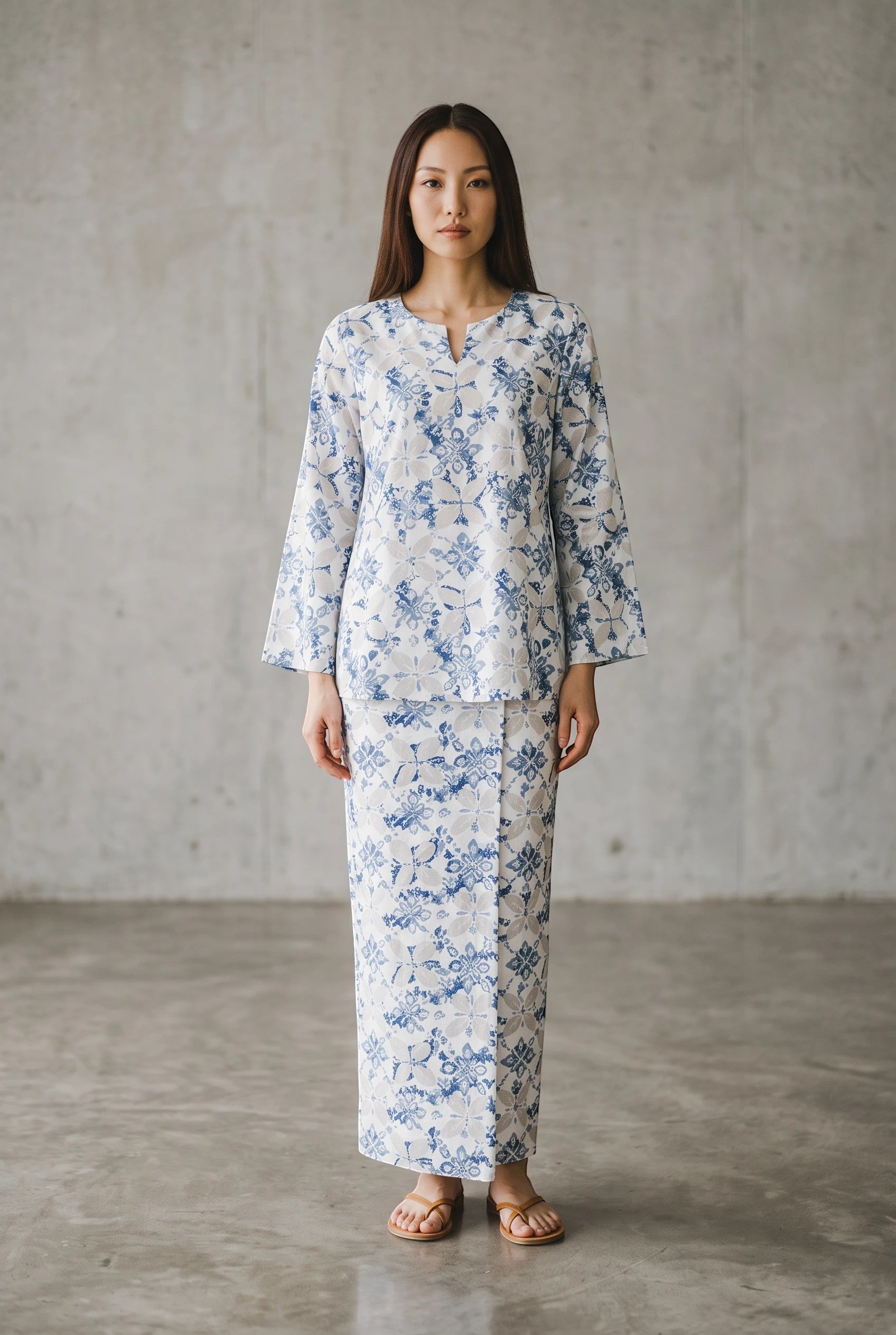 Model wearing a PARCA white and blue patterned cotton midi top and matching maxi sarung with a round V-neckline.